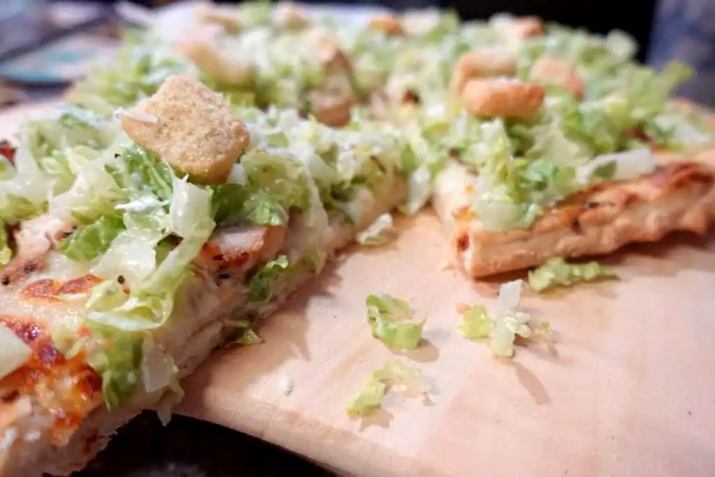 chicken-caesar-salad-pizza-on-pizza-peel-with-slices