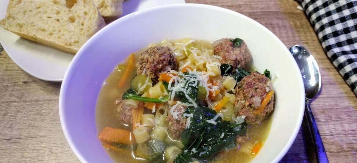 italian wedding soup in a white bowl with homemade bread