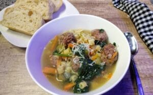 italian wedding soup in a white bowl with homemade bread