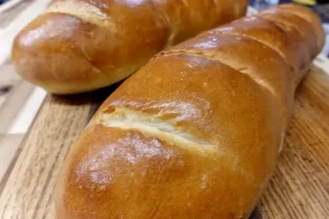 Two-golden-loaves-of-easy-homemade-French-bread-sliced-on-a-wooden-cutting-board