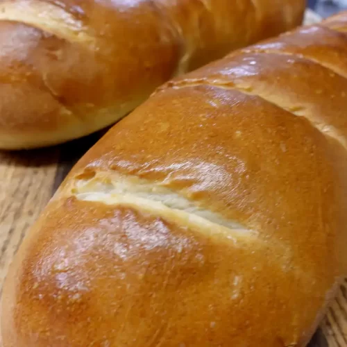 Two-golden-loaves-of-easy-homemade-French-bread-sliced-on-a-wooden-cutting-board
