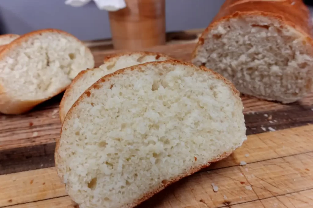 Two-golden-loaves-of-easy-homemade-French-bread-sliced-on-a-wooden-cutting-board-with-soft-fluffy-centers-visible.