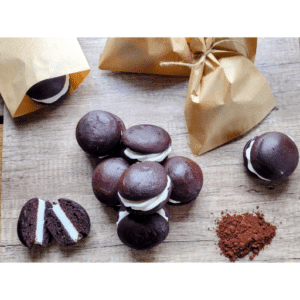 chocolate whoopie pies on wooden table with one cut in half