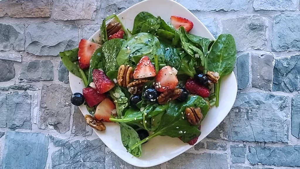 strawberry spinach salad on white plate