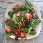 strawberry spinach salad on a white plate