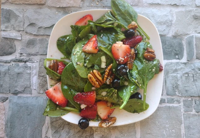 strawberry spinach salad on a white plate