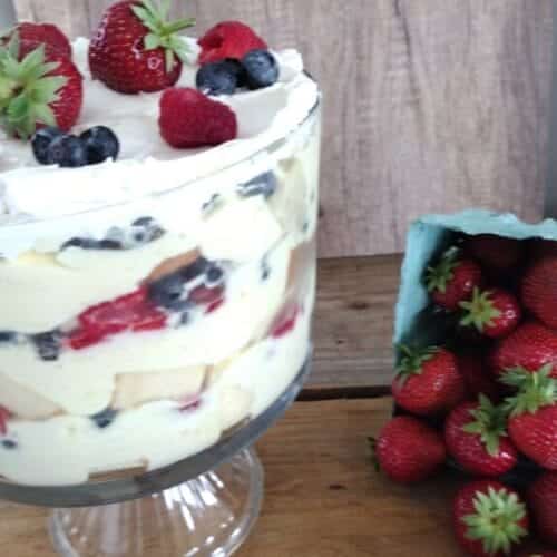 3 berry trifle with fresh strawberries falling out of basket