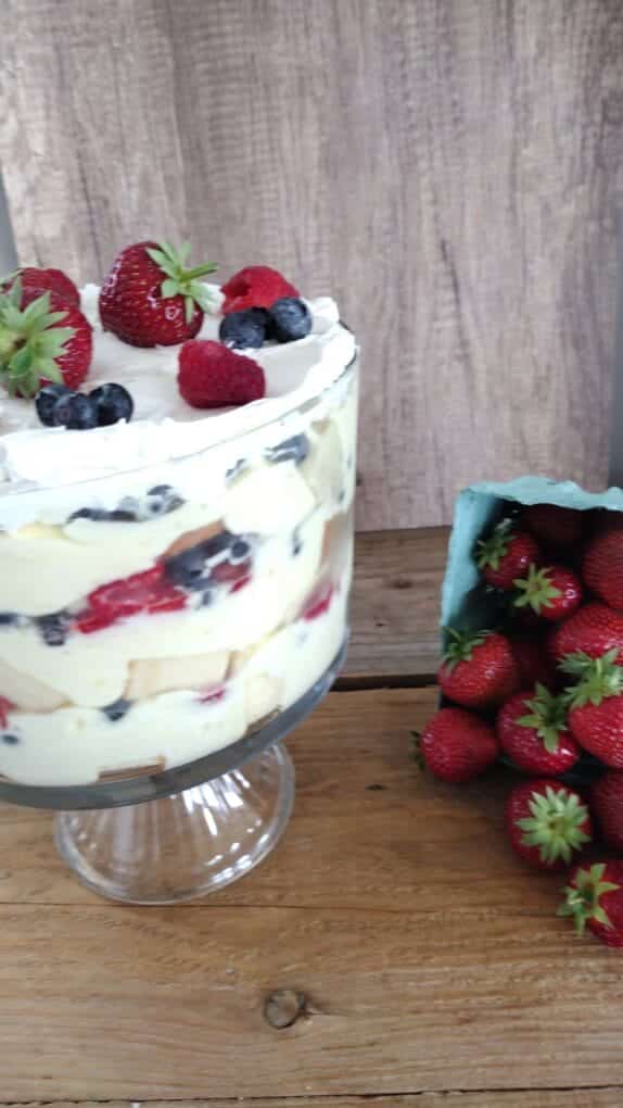 3 berry trifle with fresh strawberries falling out of basket