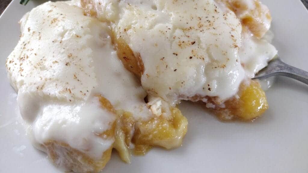 peach cobbler on white plate with a fork