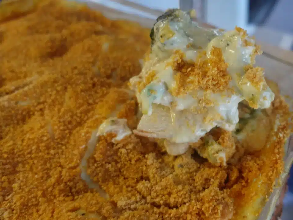 chicken broccoli casserole in clear dish with spoon being taken out