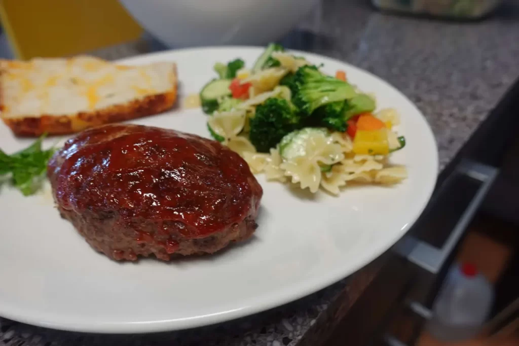 meatloaf on plate with pasta salad and cheese bread