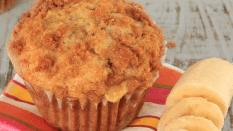 banana muffin on pink striped napkin with sliced bananas