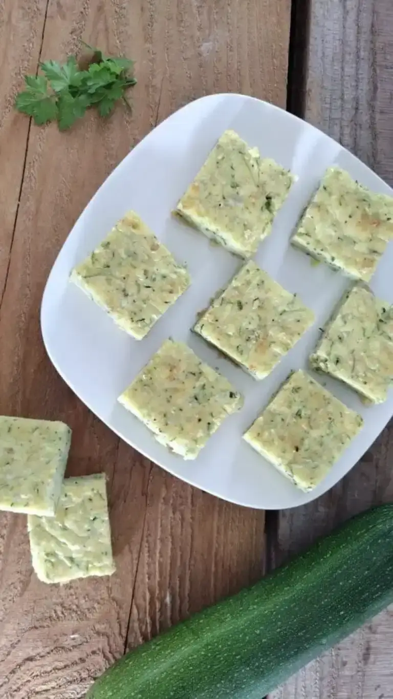 zucchini bars on white plate whole zucchini alongside