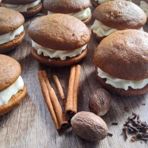 pumpkin whoopie pies with cinnamon sticks and nutmeg in front of