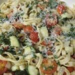 pasta with zucchini and tomatoes in white serving dish