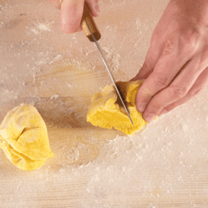 cutting homemade pasta disc into 4 pieces