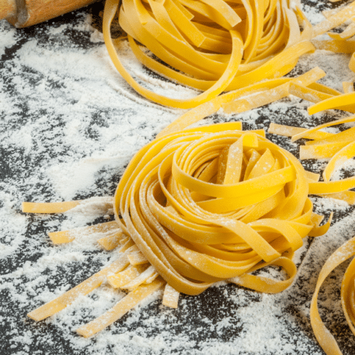 homemade pasta on floured surface noodles in 4 piles