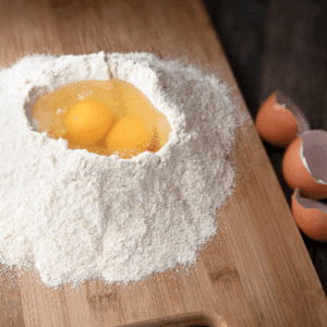 flour with eggs in middle on cutting board for homemade pasta 