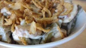 green bean casserole with french's onions on top in a white serving dish