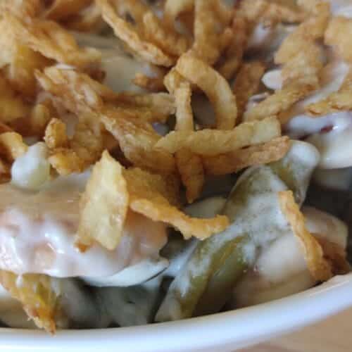 green bean casserole with french's onions on top in a white serving dish