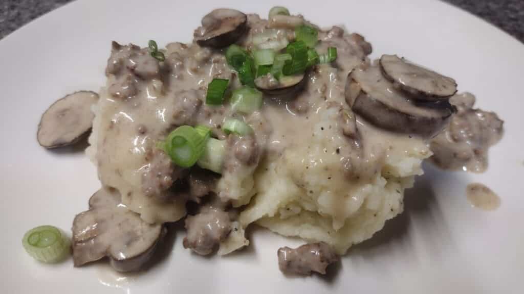 hamburg gravy served over mashed potatoes with sliced green onions on top