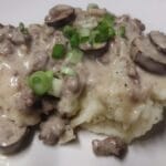 hamburg gravy served over mashed potatoes with sliced green onions on top