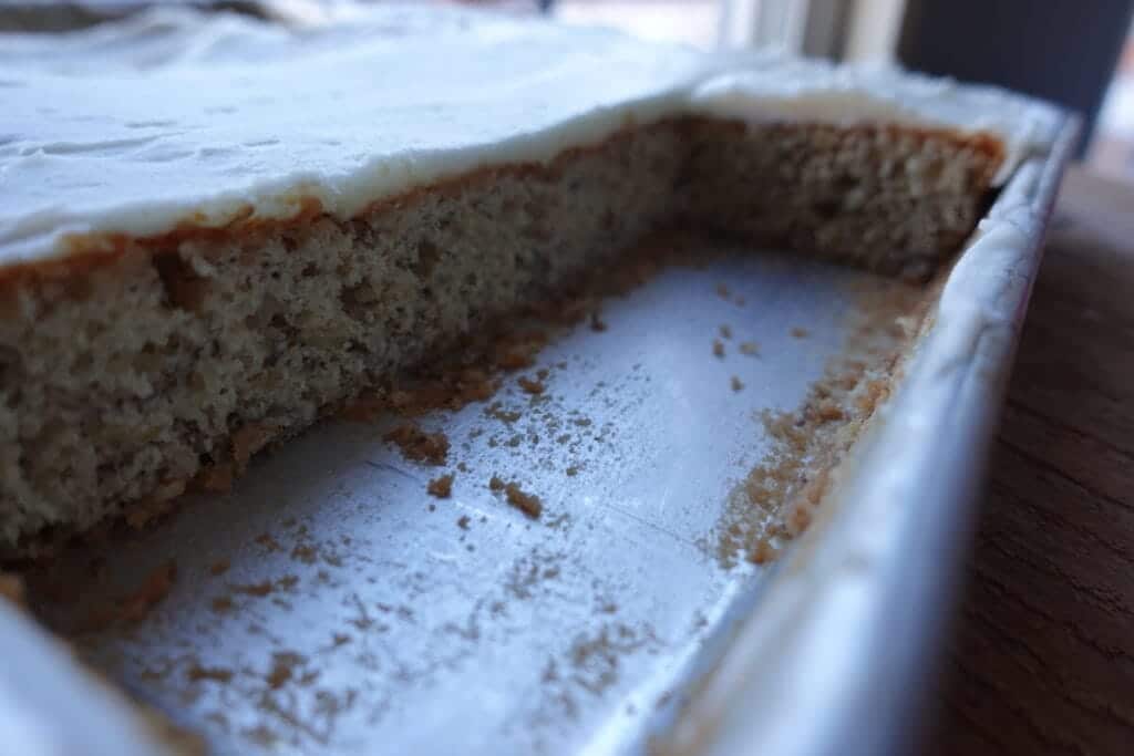 banana bars with cream cheese frosting in a baking sheet with several pieces cut out