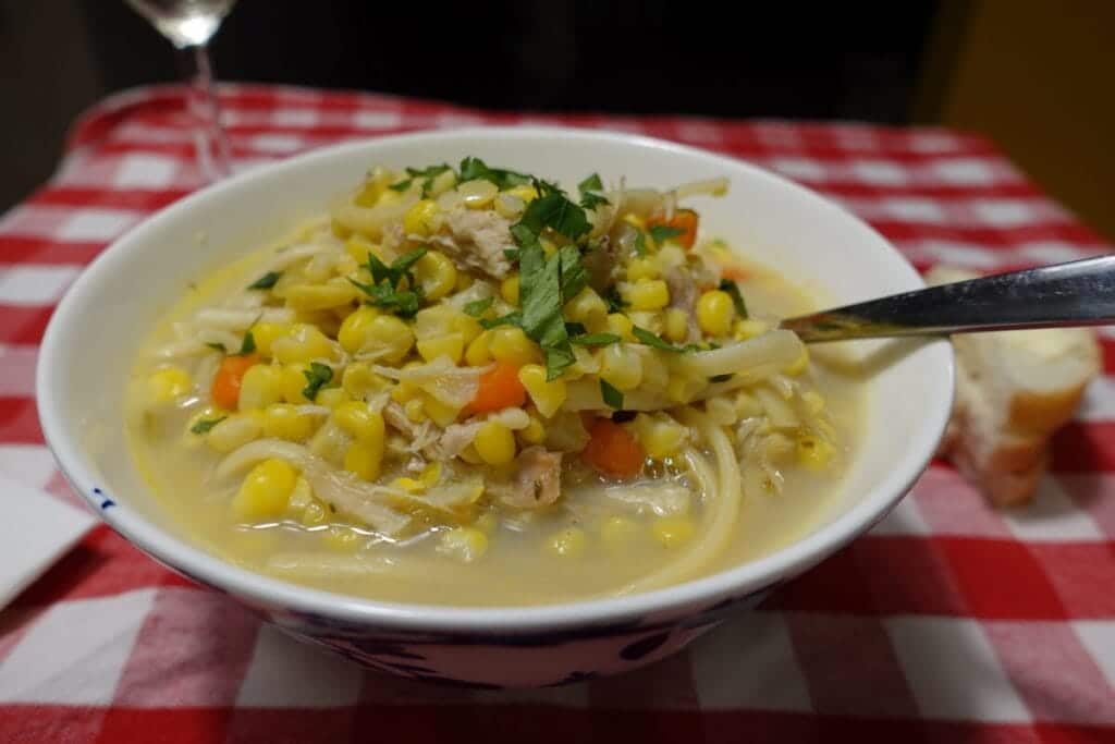 chicken corn soup on a red white checkered table cloth