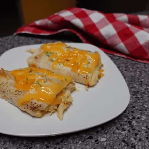 cheesy chicken enchiladas on a white plate