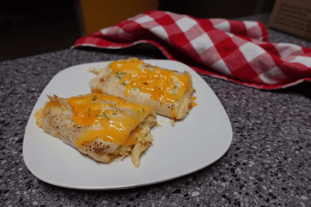 cheesy chicken enchiladas on a white plate