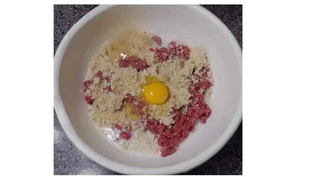 ground beef, bread crumbs eggs seasoning in white bowl for meatball mixture