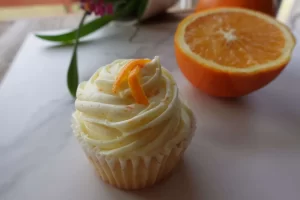 orange creamsicle cupcake on marble top with cut orange