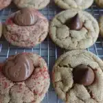 peanut butter blossoms cookies on rack with chocolate hearts and red sugar and hershey kisses white sugar