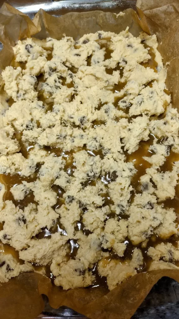 dough spread on top caramel on chocolate chip caramel bars 