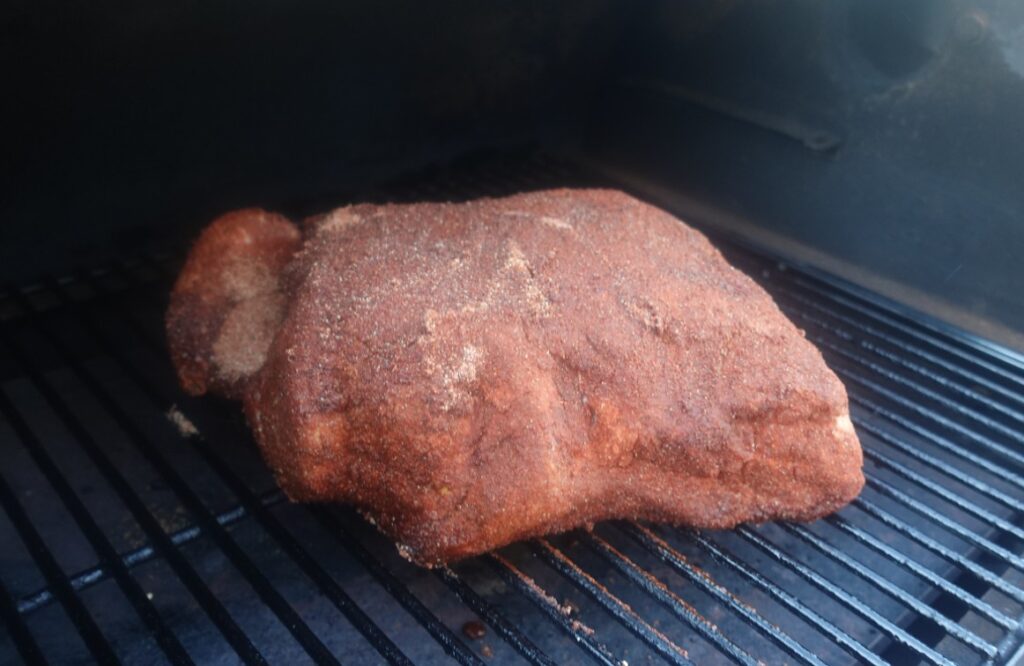 pork butt on smoker rubbed with dry rub