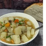 hamburger potato soup recipe served in a white bowl with a side of homemade bread