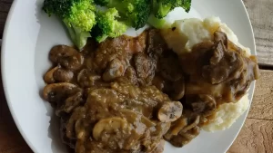 salisbury steak with mushroom gravy and mashed potatoes on white plate