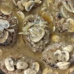 salisbury steak cooking in a cast iron skillet