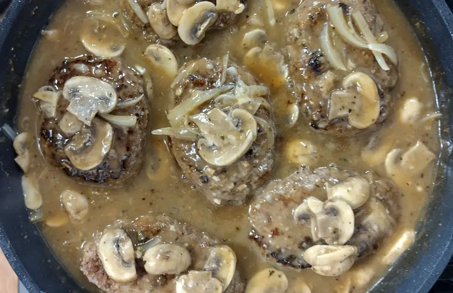 salisbury steak cooking in a cast iron skillet