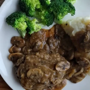 salisbury steak recipe on a white plate with mashed potatoes and broccoli