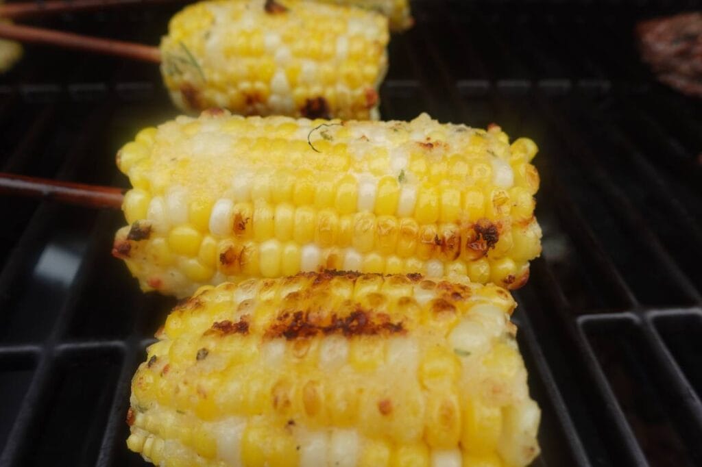 Grilled corn on the cob recipe on the grill with skewers