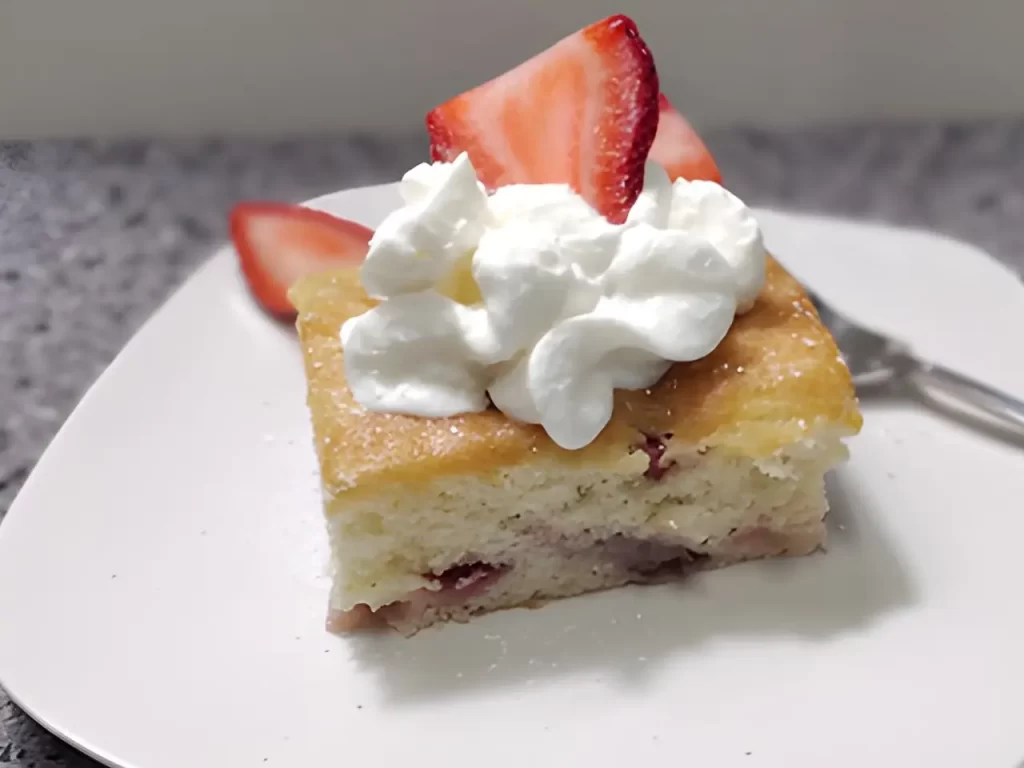 strawberry shortcake cake recipe on white plate with whipped topping and fresh strawberries