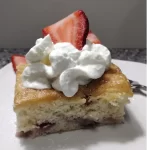 strawberry shortcake cake recipe on white plate with whipped topping and fresh sliced strawberries