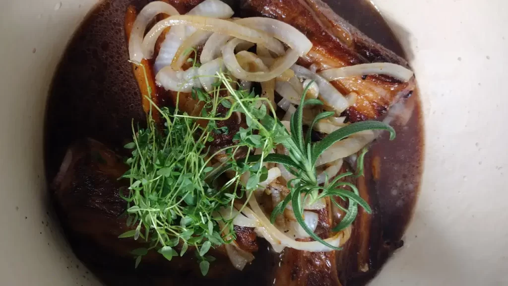 braised short ribs in pot with fresh thyme and rosemary