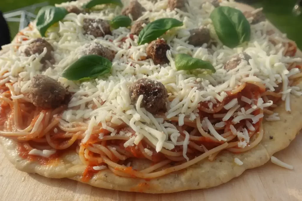 spaghetti and meatball pizza recipe with mozzarella cheese and basil leaves