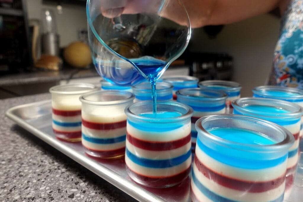 pouring blue layer on layered jello cups recipe