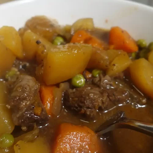 beef stew with carrots, beef, potatoes and onions and peas in serving dish