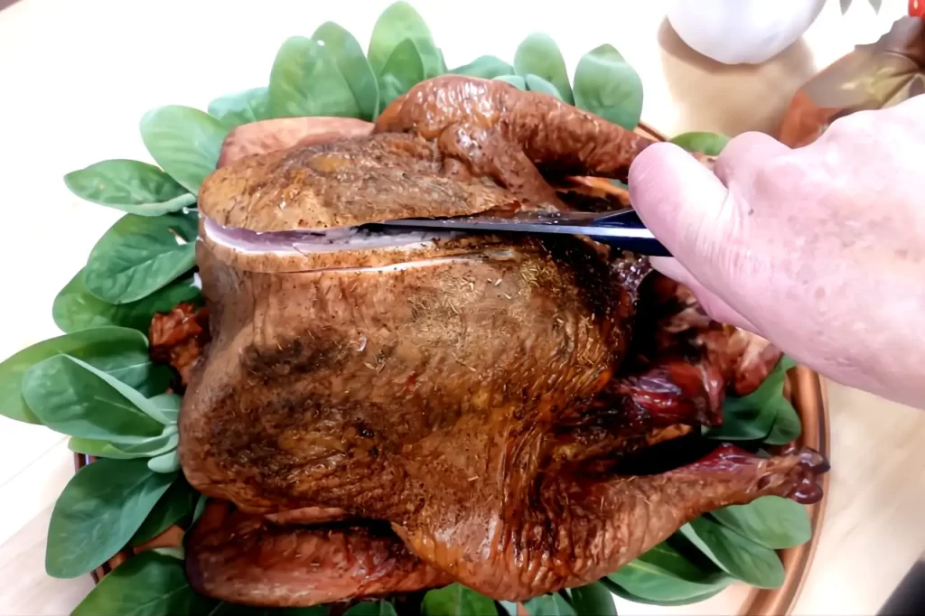 top-view-of-smoked-turkey-on-bed-of-sage-being-carved