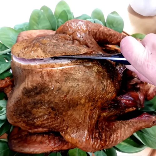 top-view-of-smoked-turkey-on-bed-of-sage-being-carved