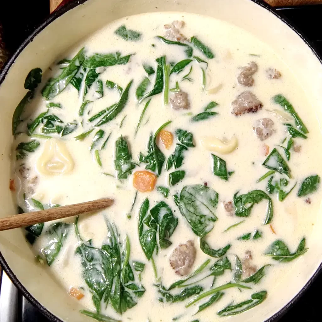 top-view-tortellini-soup-in-dutch-oven-with-sausage-spinach-carrots.